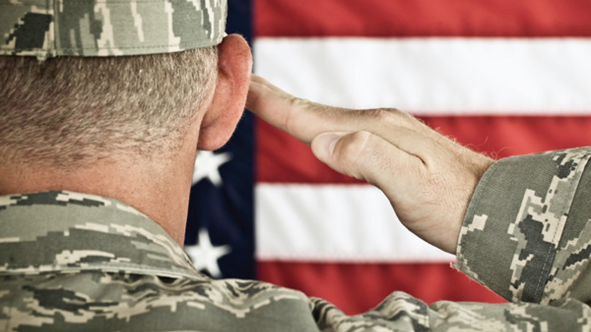 Military personnel saluting to U.S. flag
